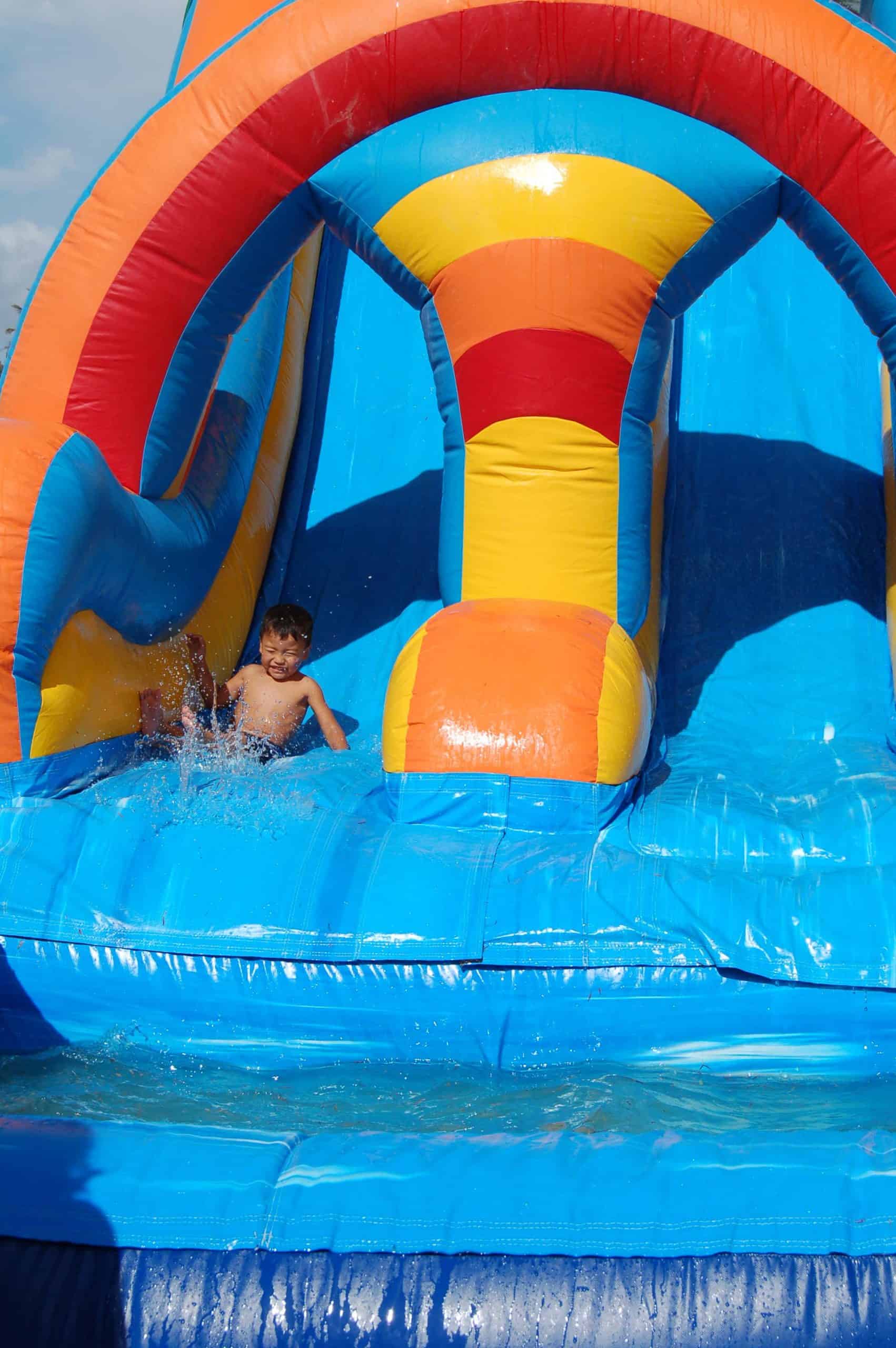 Colorful inflatable water slide with rainbow arch and splash pool for outdoor parties and events